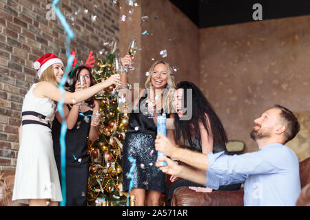 Les jeunes gens heureux s'amusant à Ney an de confettis et champagne en loft moderne Banque D'Images
