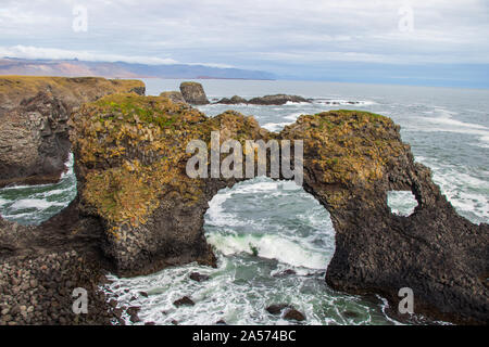 Rock bridge dans la mer dans les vagues de l'Islande Banque D'Images