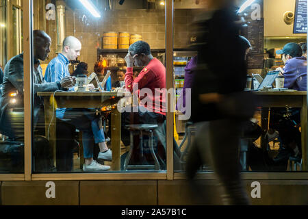 Les clients travailler et profiter de la connexion Wi-Fi gratuite dans un café à Chelsea à New York le mardi, Octobre 8, 2019. Le wi-fi et les tables communes encouragent l'utilisation de la cafétéria comme un espace de co-working. (© Richard B. Levine) Banque D'Images