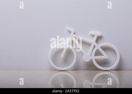 Close-up d'un symbole de vélo s'appuyant sur mur blanc Banque D'Images