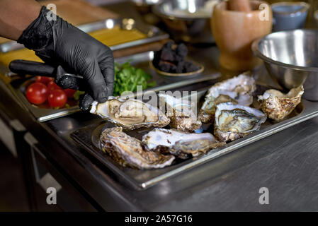 Concept alimentaire. Un chef est la cuisson des huîtres et des ingrédients pour un plat sur une table dans la cuisine. Le processus de cuisson de spaghettis aux fruits de mer. Banque D'Images