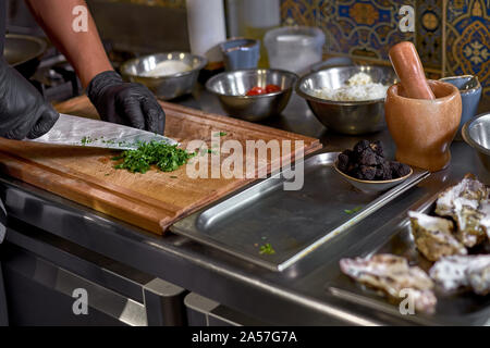 Concept alimentaire. Le chef des verts coupes fines herbes , prépare les ingrédients pour le plat sur la table de la cuisine. Le processus de la cuisson des spaghettis wit Banque D'Images