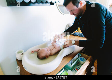 Un nouveau papa change son nouveau-nés couche sur une table à langer Banque D'Images