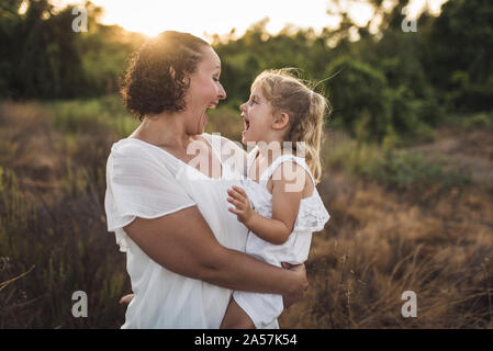 D'énormes sourires tandis que la maman a 4 ans debout dans une prairie ensoleillée Banque D'Images