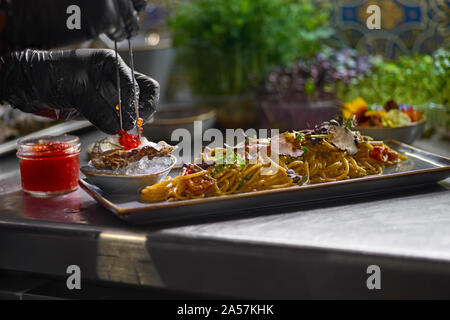 Concept alimentaire. Le chef des garnitures avec du caviar rouge un plat de spaghetti de fruits de mer. Focus sélectif. Profondeur de champ. Banque D'Images