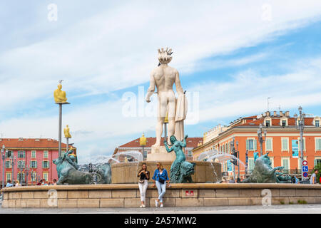 Deux femmes se détendre en face de la statue d'Apollon à la fontaine du soleil dans la Place Masséna, dans la ville de Nice France, sur la côte d'Azur. Banque D'Images