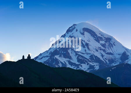 Le mont Kazbek (5047m), le troisième plus haut sommet de la Géorgie, à la frontière de la Russie, avec l'église de trinité Gergeti sur ses pentes. La Géorgie, Caucase Banque D'Images