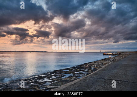 Pilier de béton à un panorama spectaculaire coucher de soleil avec des nuages à Swinoujscie, Pologne. Banque D'Images