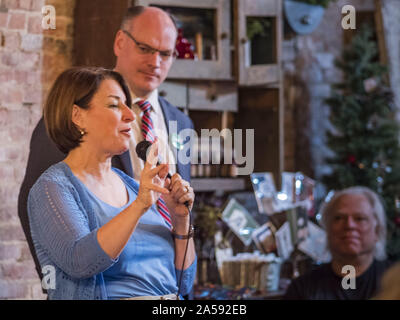 Sigourney, Iowa, États-Unis. 18 Oct, 2019. Le sénateur américain Amy Klobuchar (D-MN) parle de l'Iowa à l'arrêt de la campagne de Sigourney, IA, alors que son mari, John BESSLER, se tient derrière elle. Sen. Klobuchar est sur barnstorming bus tour du sud-est de l'Iowa cette semaine. Elle fait campagne pour être le candidat démocrate pour la présidence des États-Unis. En plus d'événements d'accueil et de la campagne, elle s'arrêta à une usine de biocarburants pour en savoir plus sur les difficultés que les agriculteurs et producteurs de biocarburants doivent faire face à cause de la guerre commerciale avec la Chine. L'Iowa détient la première épreuve de sélection de l'élection présidentielle. Le caucus de l'Iowa ar Banque D'Images