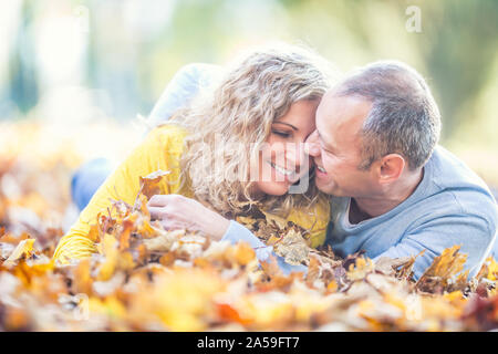 Happy senior couple lying in automne feuilles d'érable. Banque D'Images