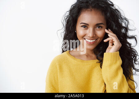 Close-up romantique féminin et tendre african american jolie femme avec les cheveux bouclés, porter le chandail jaune automne agréable, le toucher joue et smiling Banque D'Images