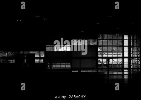 Prise de vue en niveaux de gris d'une pièce sombre avec fenêtres en verre Banque D'Images