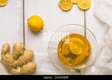 Santé, bio thé vert avec des tranches de gingembre et citron, dans une tasse en verre, photo ci-dessus à partir de la perspective de mise à plat. Il y a tout un morceau de gingembre, un wh Banque D'Images