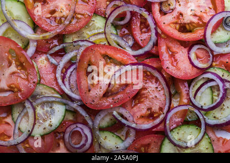 Close-up of a healthy organic salade avec tomates, concombre, oignon rouge et vu de dessus. Il y a des grains de poivre noir concassé et d'huile d'olive sur le s Banque D'Images