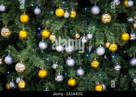 Balles multicolores d'or et d'argent suspendu à l'arbre de Noël. Décorations sur les branches de l'arbre. Banque D'Images