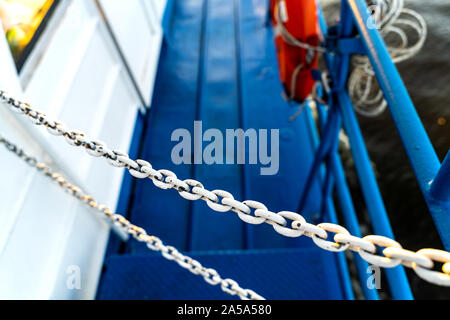 Peint blanc des chaînes sont utilisés pour bloquer le chemin comme une mesure de sécurité sur un bateau. Banque D'Images