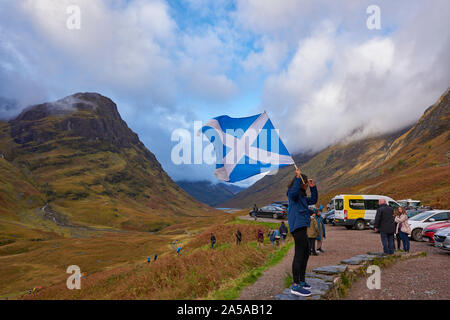 Les touristes d'une femelle photographiée tenant un sautoir écossais au parking de Glen Coe, en regard des trois soeurs sur l'A82 road. Banque D'Images