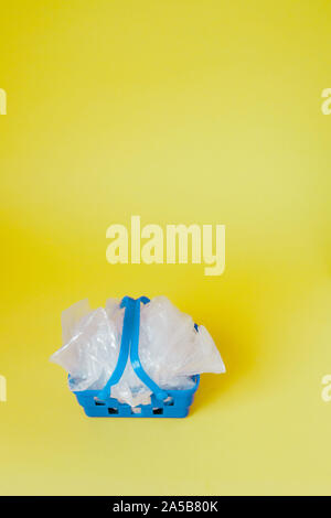 Sacs en polyéthylène dans panier sur fond jaune. Banque D'Images