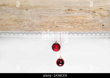 Une vieille planche en bois décoré avec de la dentelle. 2 boules de Noël rouge sont accrochés à l'avant. Fond blanc laisse beaucoup d'espace pour copier votre propre conception. Banque D'Images