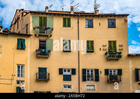 Voir de vieilles maisons aux fenêtres de l'obturateur sur la Piazza dell'Anfiteatro, dans le centre historique de Lucca, une ville médiévale en Italie. Banque D'Images