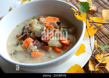 Une photo prise à la verticale d'une plaque d'une soupe aux champignons avec boletus, persil frais, chou-fleur et les carottes,sur une texture de fond feuilles serviette automne Banque D'Images