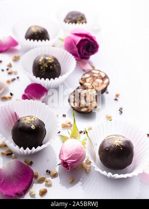Chocolats artisanaux avec les noix et miel sur fond blanc avec des pétales de rose. Shot verticale Banque D'Images