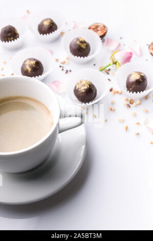 Tasse de café en céramique blanche et de confiseries au chocolat avec des écrous sur un fond blanc. Shot verticale Banque D'Images