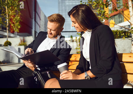 Les gens d'affaires lire signer des documents assis sur une rue de la ville. Banque D'Images