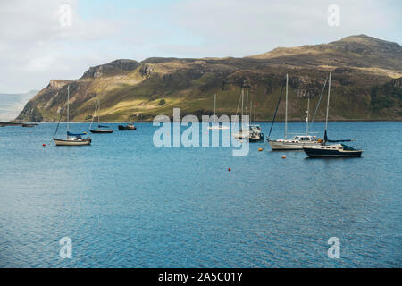 Nuages et soleil passent au-dessus de yachts amarrés dans le port de Portree, Royaume-Uni Banque D'Images