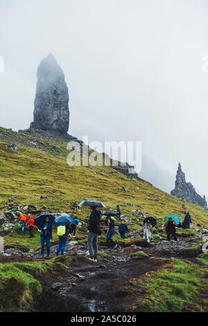 Don d'imperméables et de parapluies les touristes sur un jour nuageux, des pluies à l'ancien homme de Storr, un célèbre rock formation sur l'île de Skye, Écosse Banque D'Images