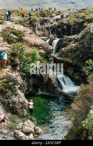 Les touristes nager et escalader les chutes d'eau et des pierres à la fée des piscines, une célèbre attraction touristique de l'île de Skye, en Ecosse Banque D'Images