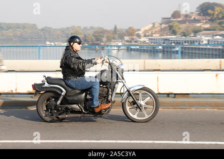 Belgrade, Serbie - 17 octobre 2019 : Un homme âgé équitation vintage retro moto sur la ville street bridge Banque D'Images