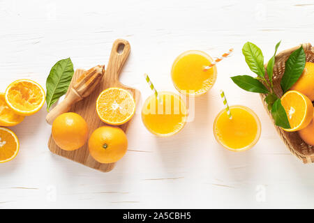 Le jus d'Orange. Du jus de fruits fraîchement pressés dans les verres et les fruits frais avec les feuilles, vue de dessus Banque D'Images
