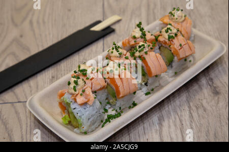 Uramaki sushi japonais. Rouleau rouleaux Bebi Riz farci aux crevettes tempura, avocat, laitue hachée, l'oignon, croustillant de saumon flambé topin, anticuchera s Banque D'Images