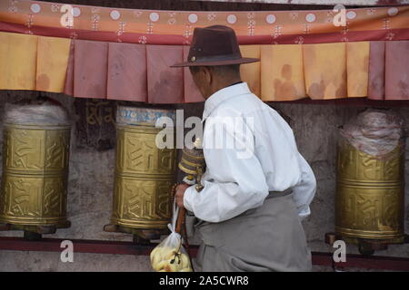 L'homme marchant à côté tibétain roues de prière à proximité du palais du Potala, Tibet en Ljhasa Banque D'Images
