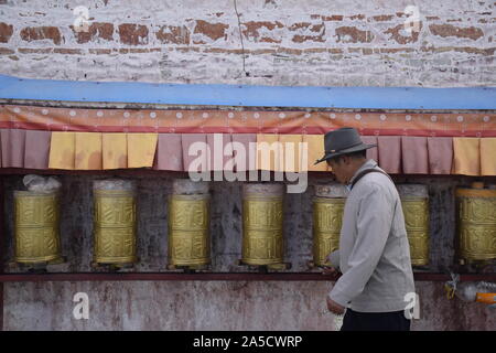 L'homme marchant à côté tibétain roues de prière à proximité du palais du Potala, Tibet en Ljhasa Banque D'Images