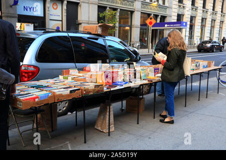 Les gens parcourant utilisé des livres à un libraire de trottoir à New York City Banque D'Images