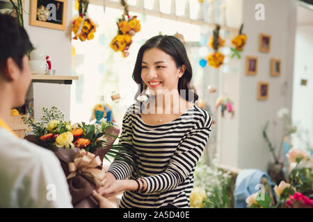 Donner fleuriste bouquet de fleurs à la femme dans le magasin de fleurs Banque D'Images