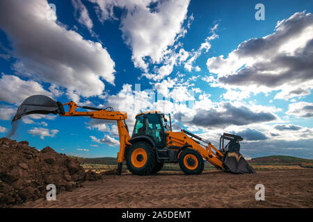 Pelle chargeuse avec arrière-plan sur le terrain au cours de travaux de terrassement, construction bâtiment Banque D'Images