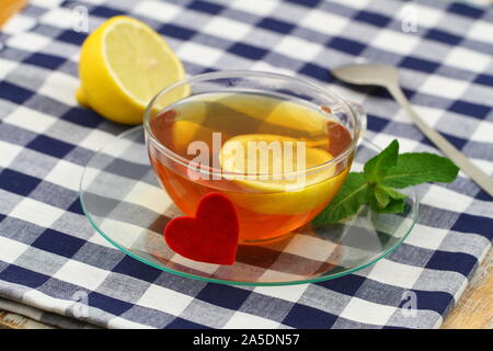 Tasse de thé au citron à la menthe fraîche et de feuilles en tissu à carreaux cœur rouge sur Banque D'Images