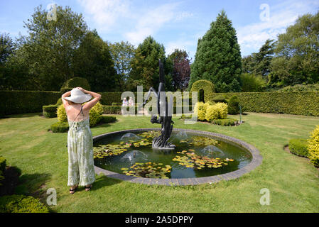 Visiteurs ou touristes admirer l'étang ornemental ronde & Statue de Icarus au jardin de Heroes & Villains Dorsington Stratford-upon-Avon en Angleterre Banque D'Images