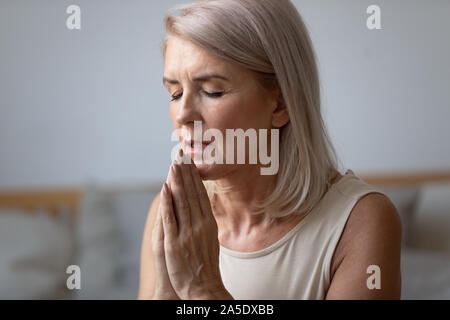 Femme d'âge moyen fidèles religieux priant seul à la maison Banque D'Images