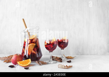 Poinçon de grâce ou de sangria à Pitcher et verres avec des feuilles sèches sur tableau blanc, copie de l'espace. Vin rouge d'automne de fruits boisson pour les vacances. Banque D'Images