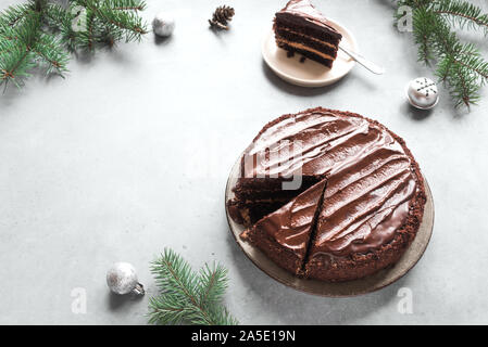 Gâteau de Noël au chocolat sur fond gris clair, vue du dessus, copiez l'espace. Gâteau au chocolat classique avec le chocolat noir et branches de sapin de Noël. Banque D'Images