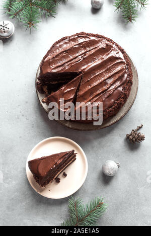 Gâteau de Noël au chocolat sur fond gris clair, vue du dessus, copiez l'espace. Gâteau au chocolat classique avec le chocolat noir et branches de sapin de Noël. Banque D'Images