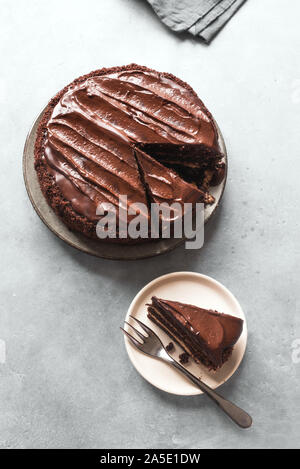 Gâteau au chocolat avec des morceaux coupés sur fond gris clair, vue du dessus, copiez l'espace. Gâteau au chocolat classique avec ganache au chocolat noir. Banque D'Images