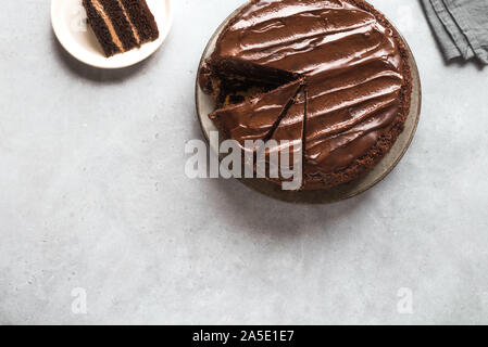 Gâteau au chocolat avec des morceaux coupés sur fond gris clair, vue du dessus, copiez l'espace. Gâteau au chocolat classique avec ganache au chocolat noir. Banque D'Images