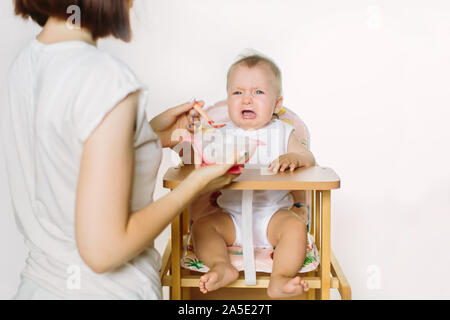 Maman nourrir le bébé. L'enfant pleure. Banque D'Images