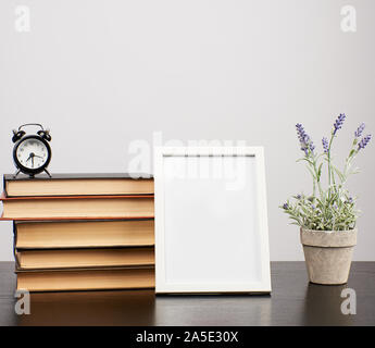 Cadre photo blanc vide, de la pile de livres et un pot de lavande en croissance sur un tableau noir Banque D'Images