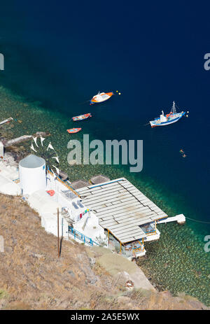 Bateaux et un moulin à vent dans le port d'Ormos Korfou, Santorin Thirasia vu de l'angle. Banque D'Images